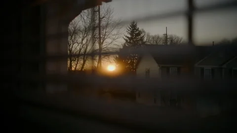 Warm sunset light shines through partially closed window blinds, creating soft Stock Footage 324759796