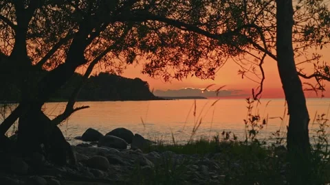 Warm sunset over the Baltic Sea on Bornholm, Denmark, with silhouetted coastal Stock Footage 345688062