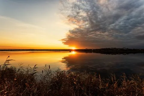 Warm sunset over a lake with dramatic clouds after a thunderstorm Stock Photos
