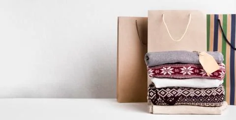 Warm sweaters with patterns and tag for text laying on white Photos