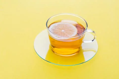 Warm tea with lemon slice in clear cup on yellow background during daytime Stock Photos