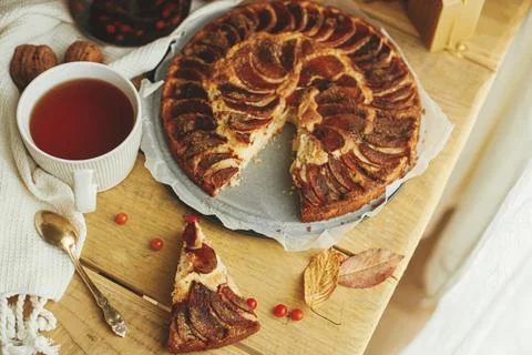 Warm tea in stylish cup on rustic wooden table with apple pie, candle, autu.. Stock Photos