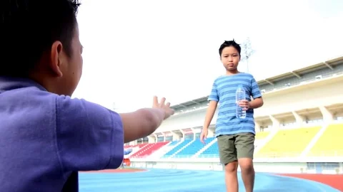 Warm tone Slow Boy give water to sitting boy 스톡 동영상 78740379