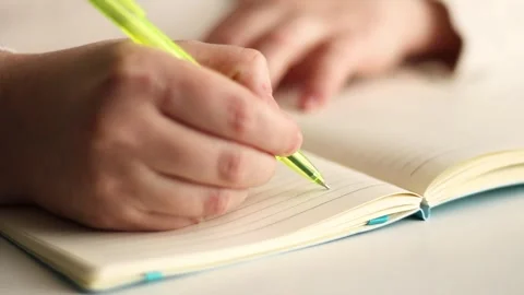 Warm toned image of hand writing personal thoughts in diary. Blurred background Stock Footage 310012166