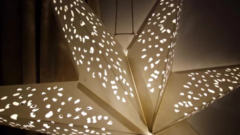 Warm-toned image of a modern star-shaped lamp casting a pattern on the walls Stock Footage 269964233