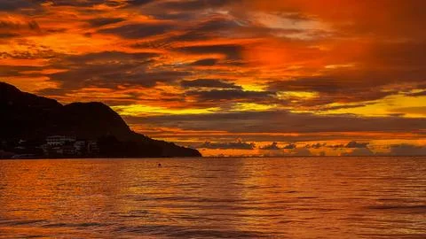 Warm Tones of Sunset Reflected on Ocean Surface with Island Silhouette Stock Photos