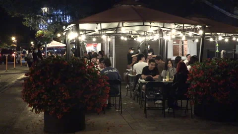 Warm ummer night with people walking and restaurant patios open post COVID 19 Vídeo Stock 158492535