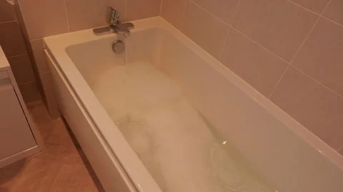 Warm water flows into a bathtub filled with bubbles Video stock 337955010
