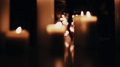 Warm white wax candles burning on floor of dark room Stock Footage