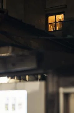 Warm window light glowing in dark urban alley Stock Photos