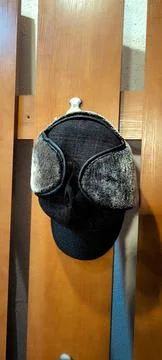Warm winter trapper hat hanging on a wooden wall rack. Foto stock