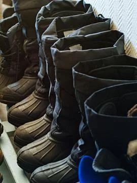Warm work shoes. Workers' winter industrial boots stand in row in drying room Stock Photos