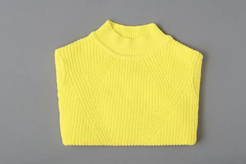 Warm yellow sweater patterned knit on gray background Stock Photos