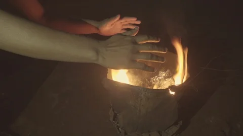 Warming up bare hands sitting in front of a bonfire during a cold winter night Stock Footage 93882608