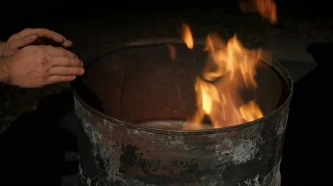 Warming hands over barrel under street light Stock Footage 57658165