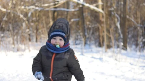 Warmly clothed 2 years old boy running forward to camera in snowy park Stock Footage 101441365