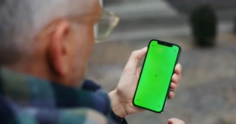 A warmly dressed man holds a green screen phone Stock Footage 175349361