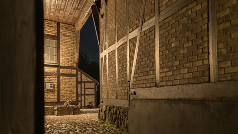 Warmly Lit Half-Timbered Cobblestone Alley at Night Stock Footage 343695680