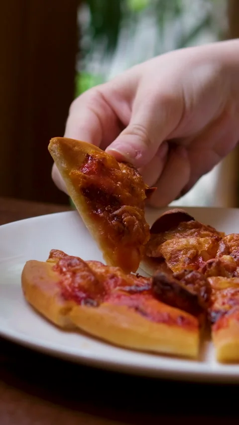 In a warmly lit setting, a hand sprinkles Parmesan cheese over a delicious Stock Footage 326464379