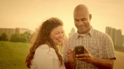 Warmly-tinted happy couple using a smart phone in Detroit 4K Stock Footage 52618641