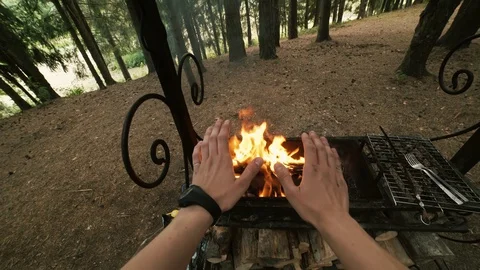 Warms his hands at the barbecue Stock Footage 129810045