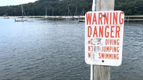 Warning-Danger NO DIVING/SWIMMING/JUMPING sing on boat dock in sunny day Stock Footage