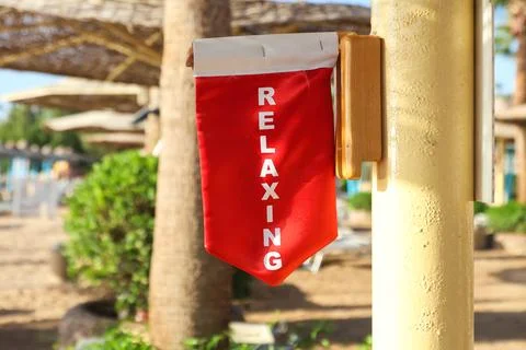 A warning flag under an umbrella on the beach with the inscription We are rel Stock-Fotos