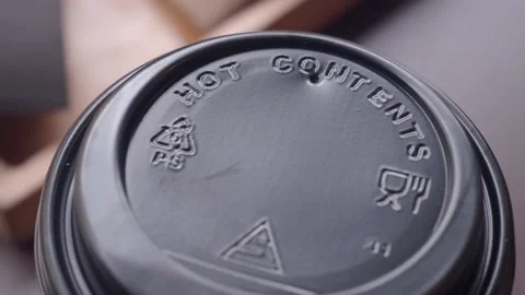 Warning label on a coffee cup lid shows hot contents caution Stock Footage 310643282