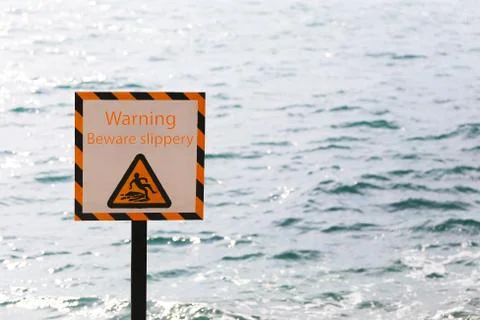 Warning labels of warning beware slippery in seaside area. Stock Photos