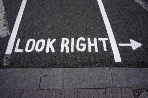 Warning message "look right" on footpath crossing street Stock Photos