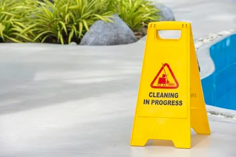 Warning plates cleaning in progress beside the pool Made of yellow plastic. Stock Photos