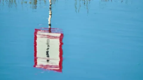 Warning road sign with an exclamation mark is reflected in the water of the r Stock Footage 169873445