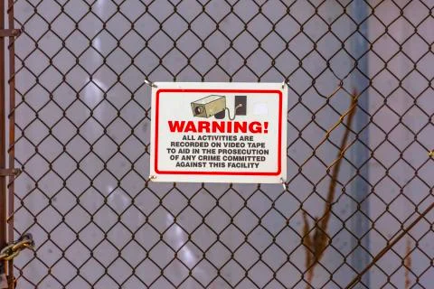 Warning security camera sign on chain link fence Stock Photos