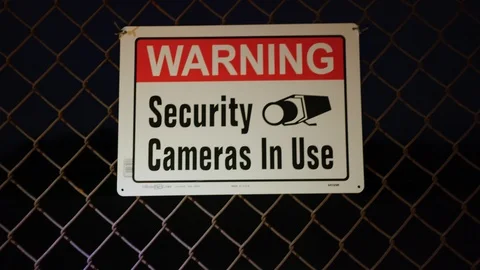 Warning Security Cameras In Use signs at fence at night Stock Footage 126688805