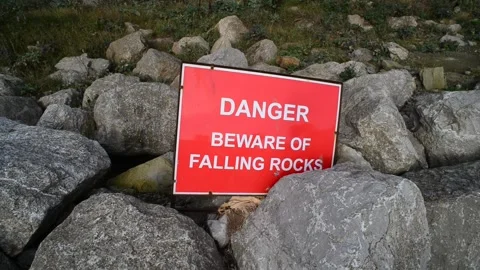 Warning sign of falling rocks below cliff at staithes uk Stock Footage 138808620