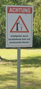 Warning sign indicating falling branches and trees in park area Stock Photos