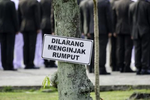 Warning sign Keep Off the Grass at public park in Indonesian Stock Photos