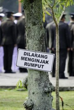 Warning sign Keep Off the Grass at public park in Indonesian Stock Photos