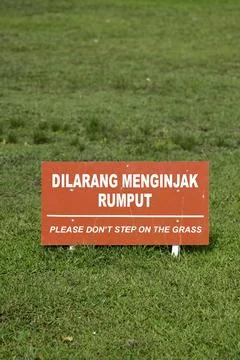 Warning sign Please Don't Step on the Grass at public park in Indonesian Stock Photos