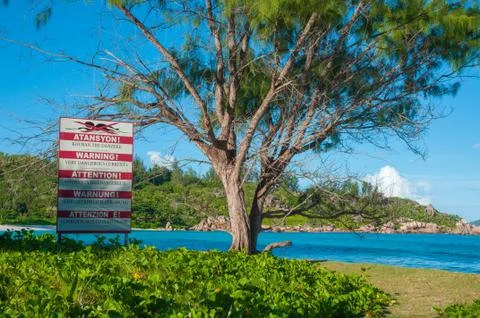Warning sign post of strong current at the beach of Anse Cocos Stock Photos