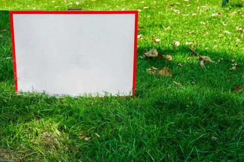 Warning table with copy space in green grass. Mock up for park or garden sign Stock-Fotos