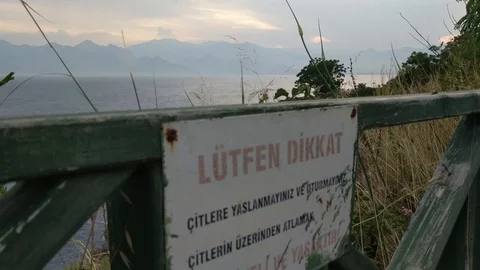 Warning table on rocky coast in the sunset Stock Footage 92912330
