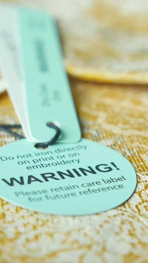 Warning tag on vibrant fabric showcasing intricate pattern design Stock Footage 308689546