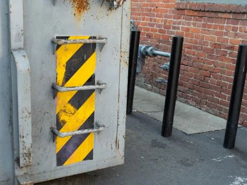 Warning tape pattern on waste dumpster outside at side of building Stock Photos