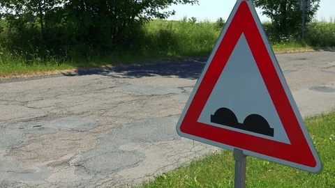Warning traffic sign about bumps in road with passing car in sunny summer day Stock Footage 79339610