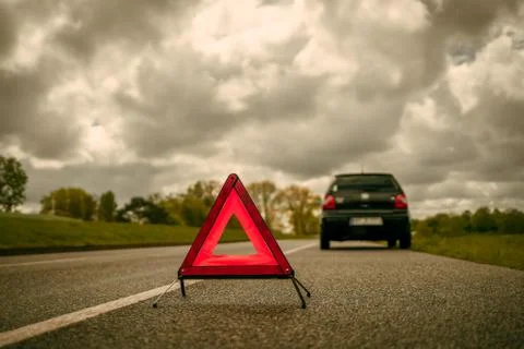 A warning triangle in front of a car with a breakdown on a side strip Stock Photos