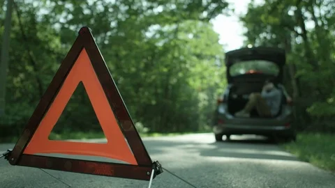 Warning Triangle. Man Sitting in the Openened Car Trunk Stock Footage 79728017