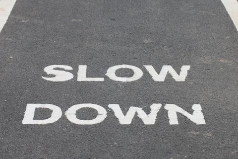 A warnning sign SLOW DOWN painted on the bike lane Stock Photos