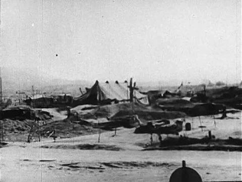 A warplane is loaded on an airfield, parachutes drop and an animation shows a Stock Footage