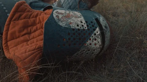 Warrior is  lying on the field with his sword, helm and other equipment. Video stock 88846488